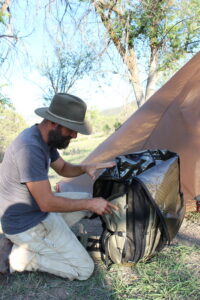 photo of Jake unzipping the Lanner backpack in front of the tent